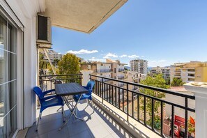 A balcony with a table and chairs, overlooking a cityscape with buildings and trees. - Flower Balcony Apartment 2BR Beachside Escape (Sarandë)