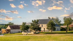 A stone building with a sloped roof, surrounded by a grassy area and trees. - La Grange - Pleasure in Nature & Calm (FLERE LA RIVIERE)