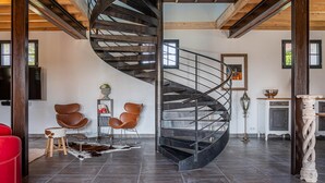 A modern interior with a spiral staircase, leather chairs, a red sofa, and a rustic rug. - La Grange - Pleasure in Nature & Calm (FLERE LA RIVIERE)