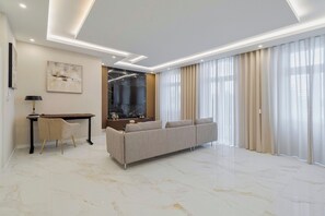 A modern living room with a sofa, a desk, and a large window with curtains. - Garrett Elegance (Setúbal)