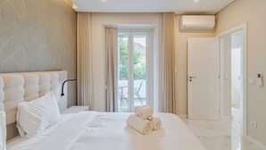 Ein modernes Schlafzimmer mit einem großen Bett, einem Blattmuster an der Kopfteil, einem Balkonblick und einer Klimaanlage.