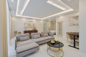 Una sala de estar moderna con un sofá seccional, una mesa de centro de vidrio y una zona de comedor con una mesa y sillas de madera.