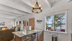 Una cocina con vista a un lago, armarios de madera, una araña y una encimera con un lavamanos.