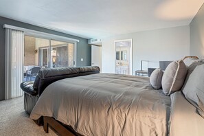 A bedroom with a large bed, a sliding glass door leading to a balcony, a small table, and a mirror. - Spacious 2Bed 2bath condo w/pool and spa! (Tucson)