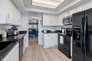 A modern kitchen with white cabinets, a black refrigerator, a microwave, and an oven. - Spacious 2Bed 2bath condo w/pool and spa! (Tucson)