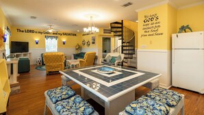 A living room with a dining table, sofas, a TV, and a staircase. - Ocean View l Big 5BR Home l Easy Beach Access (Surfside Beach)