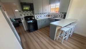 Una cucina con fornelli, forno a microonde, lavello e sgabelli da bar.