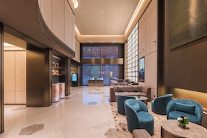 A spacious lobby with seating areas, a reception desk, and a large window.