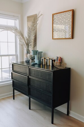 A black console with multiple drawers, a coffee machine, and decorative items on a wall-mounted cabinet. - Sunny  3-bedroom townhome with Pool in charming Lewes (Lewes)