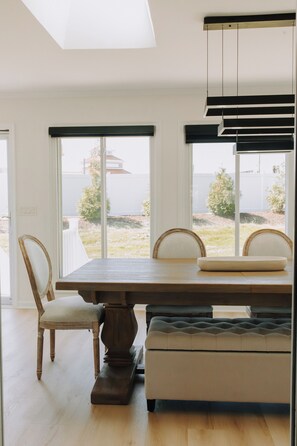 A dining area with a wooden table, two chairs, a bench, and a view through large windows. - Sunny  3-bedroom townhome with Pool in charming Lewes (Lewes)