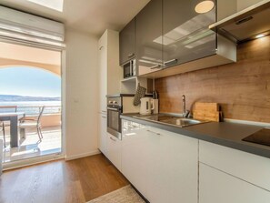 Eine moderne Küche mit Meerblick, integrierten Geräten und einer Wand im Holzdesign.