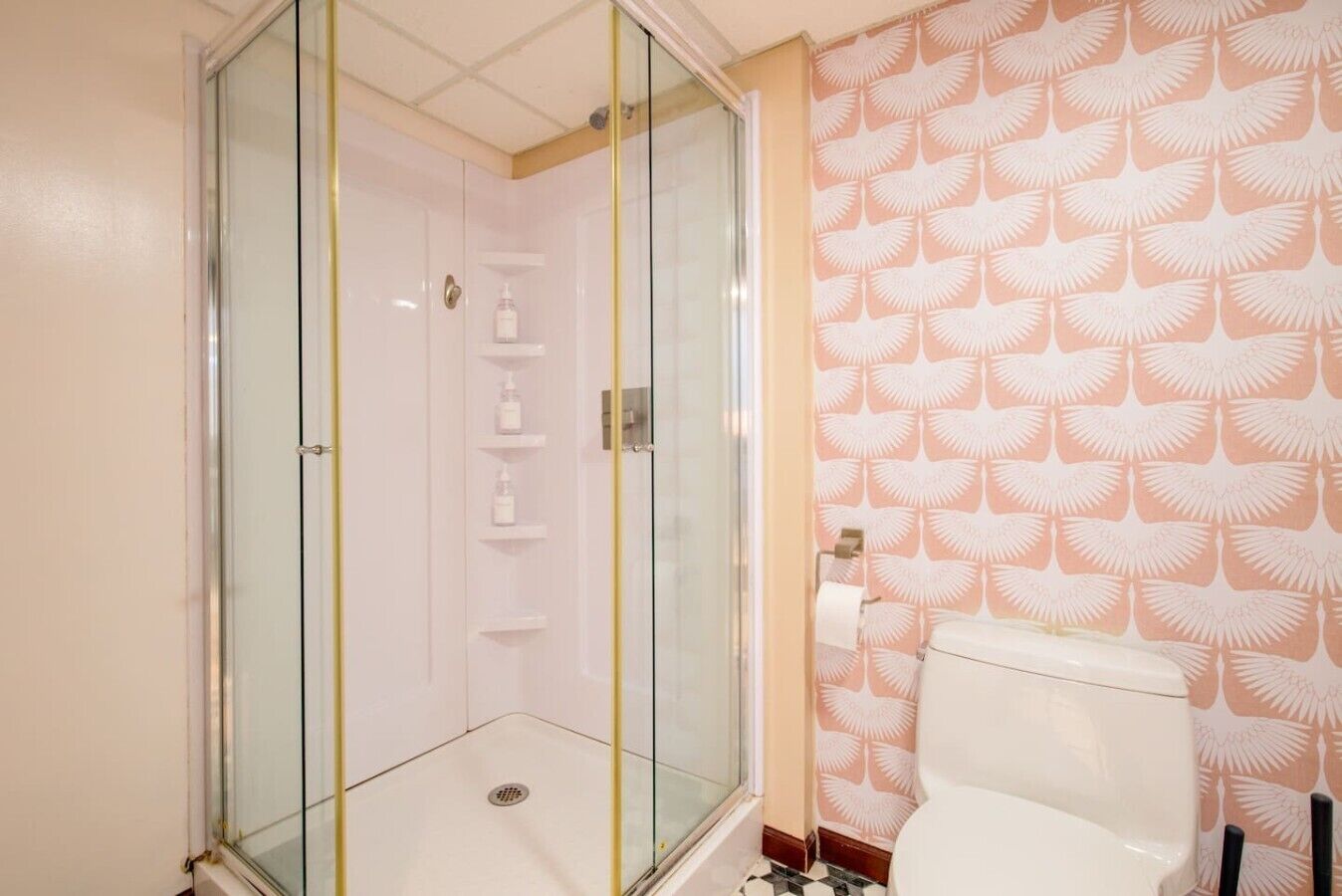 Ein Badezimmer mit einer Duschkabine, einer Toilette und einer Wand mit Muster.
