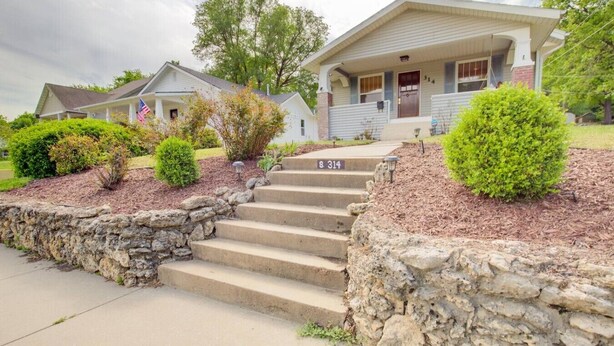 A two-story house with a front porch, stone steps, and a mailbox. - Charming Bungalow 4bd/2ba, Huge Deck and Sunroom (Manhattan)