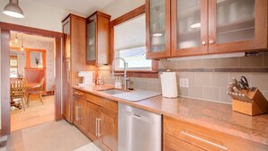 A modern kitchen with wooden cabinets, a stainless steel dishwasher, and a countertop with a knife block. - Charming Bungalow 4bd/2ba, Huge Deck and Sunroom (Manhattan)