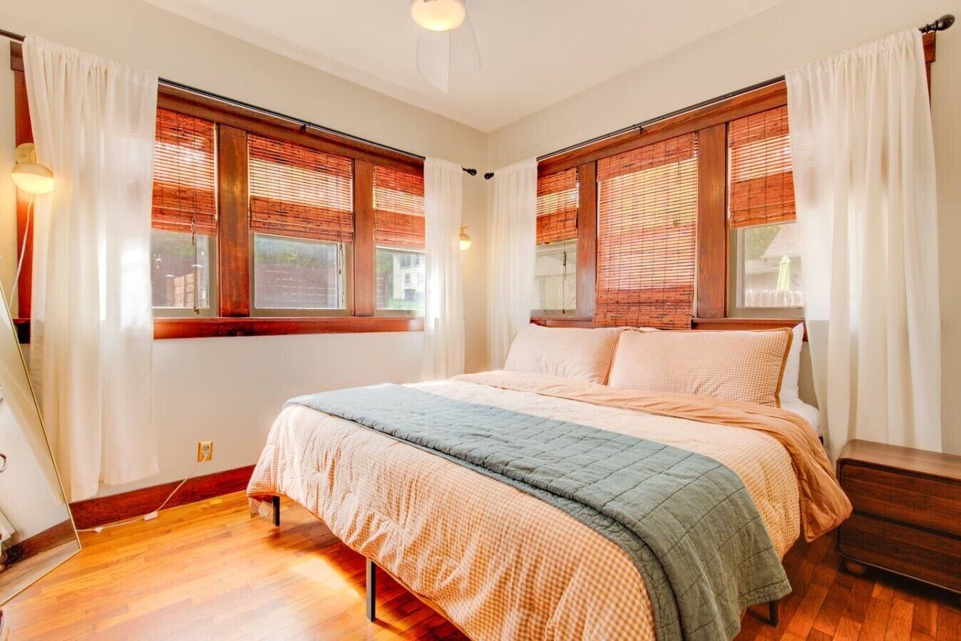 A bedroom with a bed, wooden blinds, and a window.