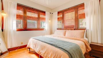 A bedroom with a bed, wooden blinds, and a window.