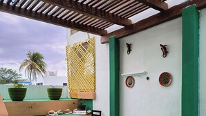 A covered patio with a wooden ceiling, a green floor, a table with chairs, and decorative plates on the wall. - Capitan Tiega House (Isla Mujeres)