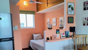 A compact kitchen with a refrigerator, a bed, a dining table, and a ceiling fan. - Capitan Tiega House (Isla Mujeres)