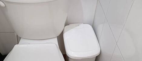 A small bathroom with a toilet and a trash bin.