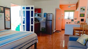 A compact room with a bed, a sofa, a kitchenette, and a dining area. - Capitan Tiega House (Isla Mujeres)