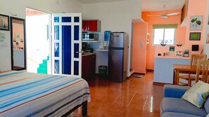 A compact room with a bed, a sofa, a kitchenette, and a dining area. - Capitan Tiega House (Isla Mujeres)