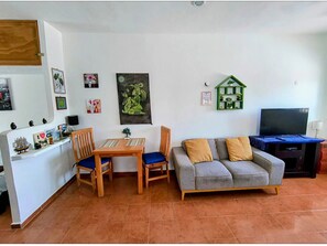A living room with a sofa, a TV, a small table, and chairs. - Capitan Tiega House (Isla Mujeres)