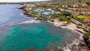 Un complejo turístico frente al mar con villas privadas, un puerto deportivo y montañas al fondo.