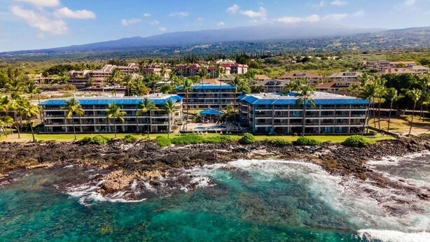 Un resort con varias edificaciones, una costa rocosa y aguas turquesas cristalinas.
