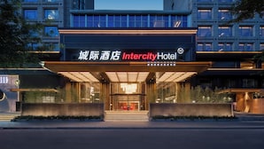 Una entrada de hotel moderna con señalización iluminada, fachada de vidrio y área de acceso estructurada.