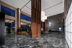 A spacious lobby with a reception desk, seating area, and large windows.