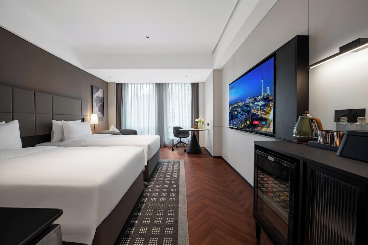 Hotellihuone, jossa on suuri sänky, työpöytä, televisio ja näkymä kaupunkimaisemaan.