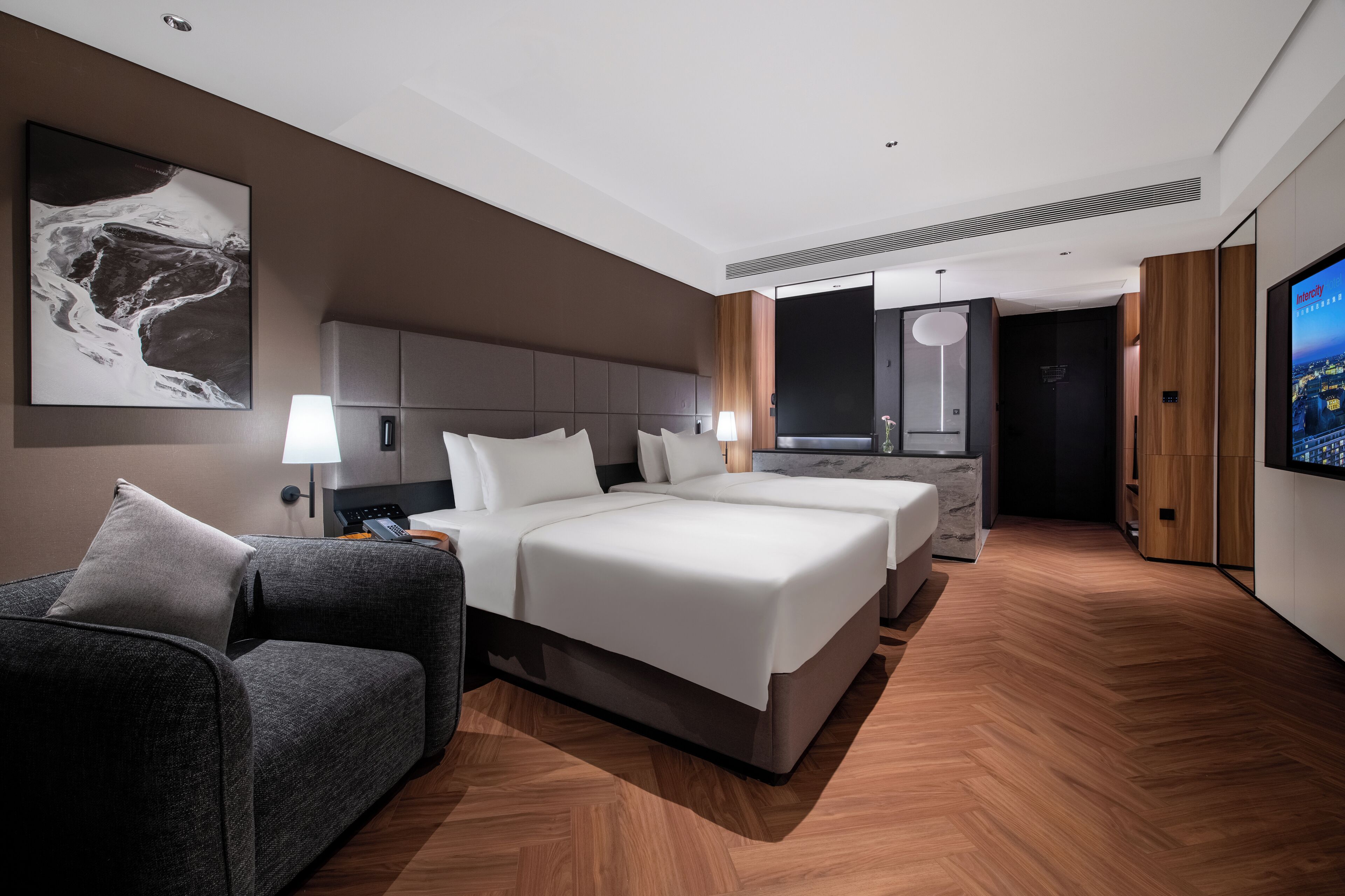 A modern hotel room with a large bed, a sofa, a TV, and a desk.
