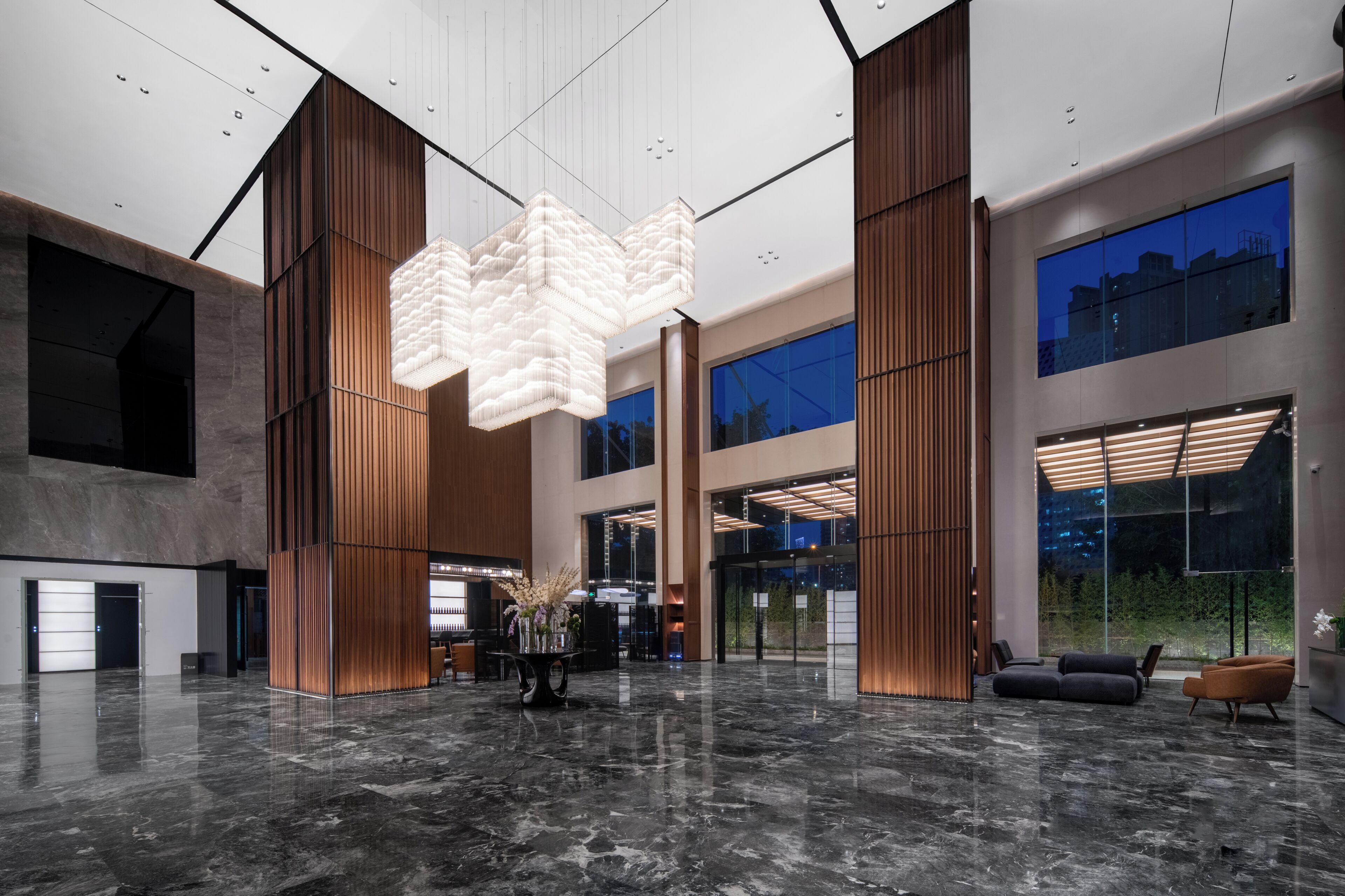 A spacious lobby with a high ceiling, a central light fixture, and seating areas.