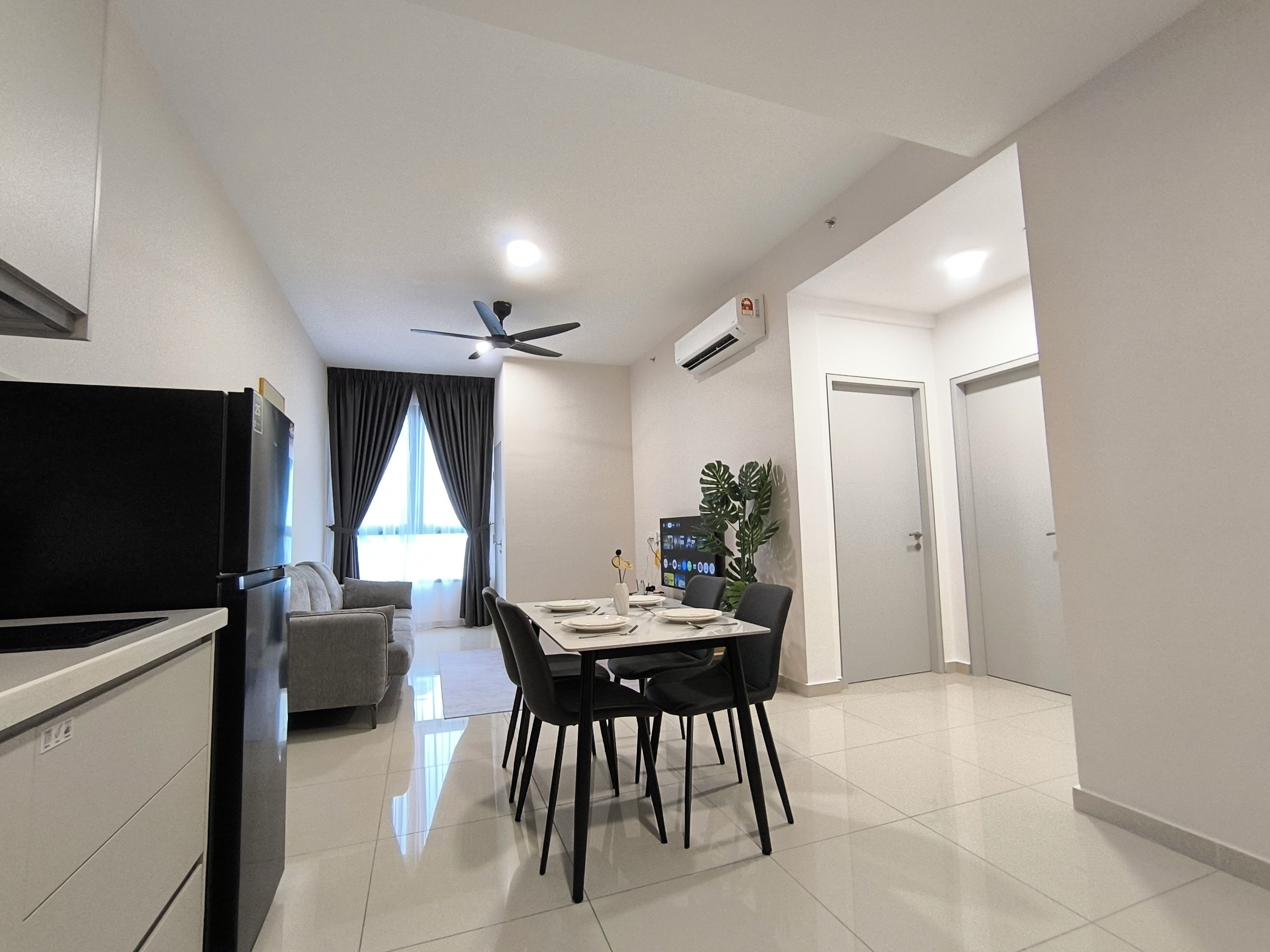A modern kitchen with a built-in refrigerator, a dining area with a table and chairs, and a ceiling fan.