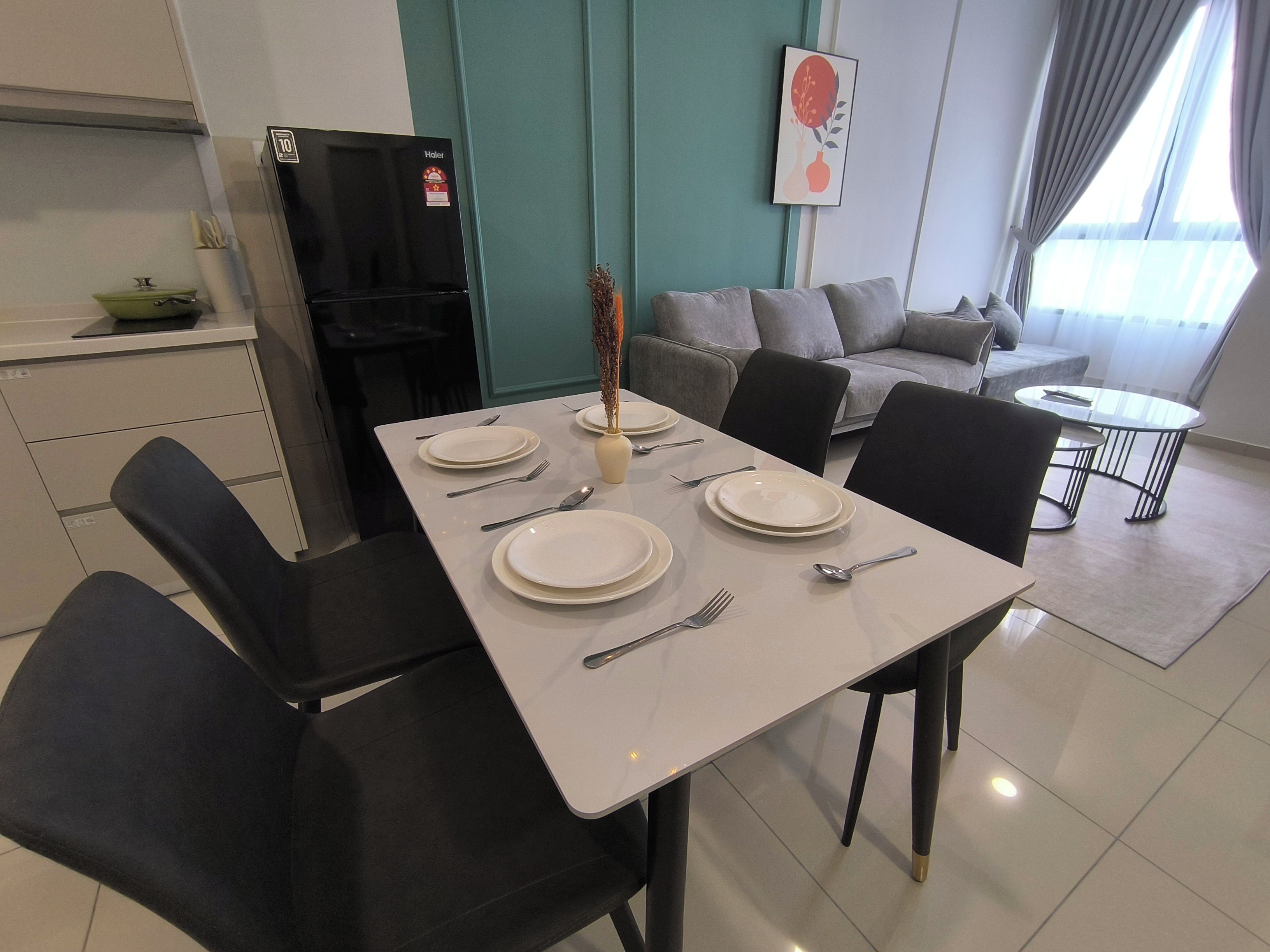 A dining area with a table set for four, a sofa, and a kitchen area with a refrigerator.