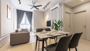 A modern dining area with a table set for four, a ceiling fan, and a flat-screen TV mounted on the wall. - BeCentral i-City by Manhattan (Shah Alam)
