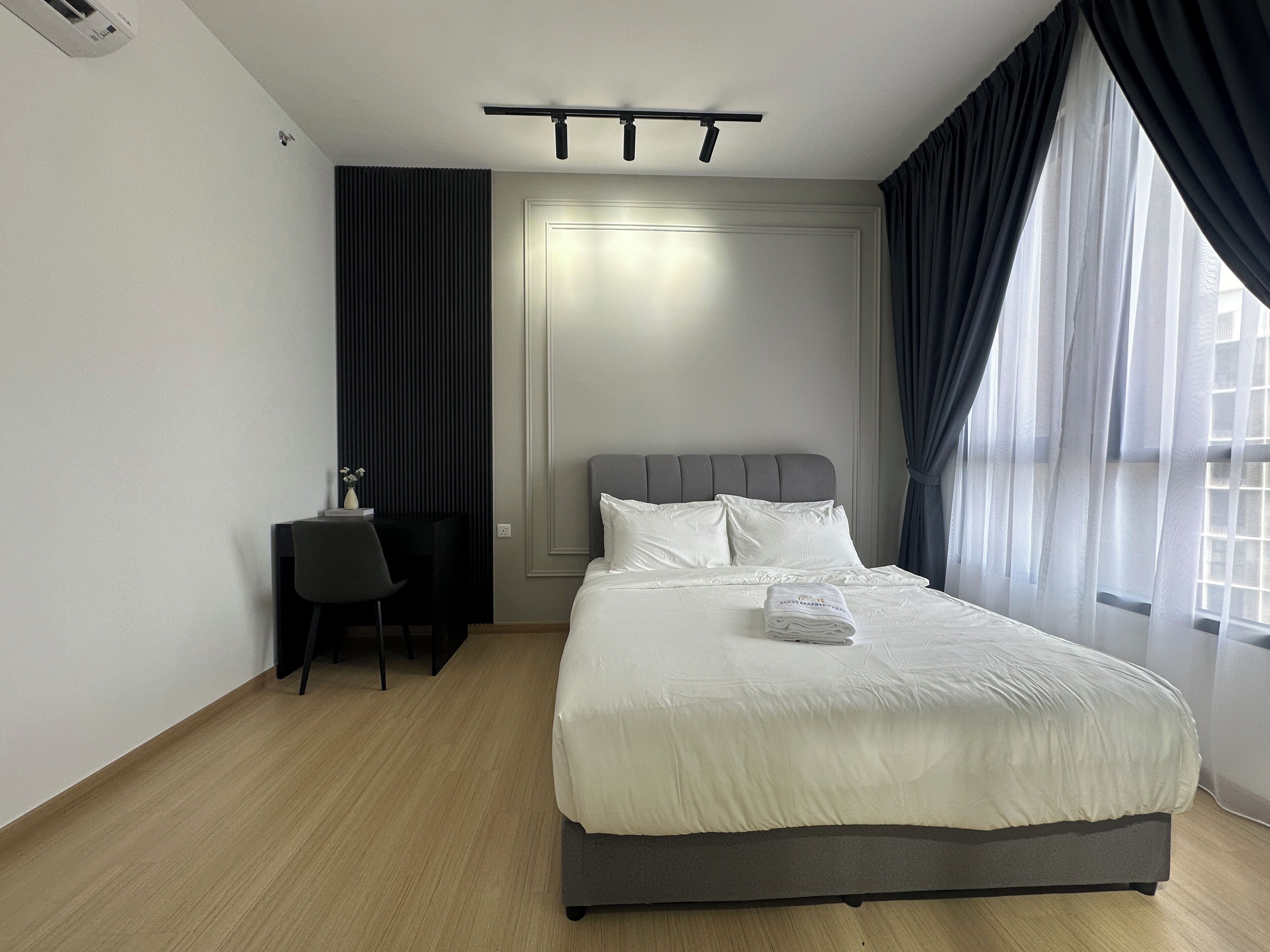 A modern hotel room with a bed, a desk, a chair, and a window with curtains.