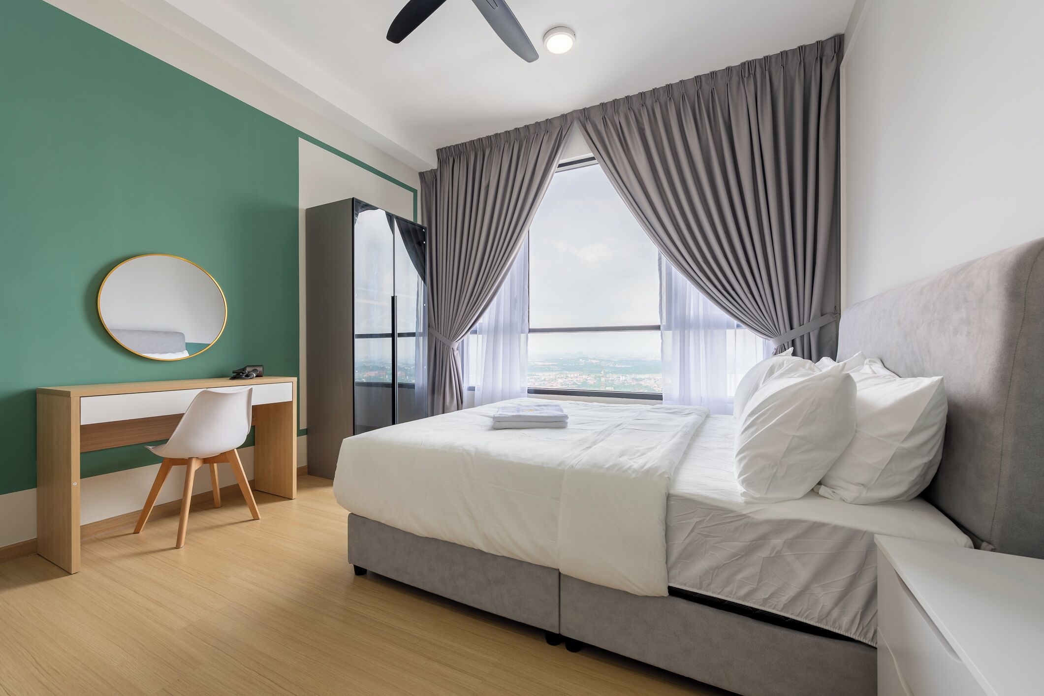 Quarto de hotel moderno com cama, escrivaninha, cadeira e vista da cidade.