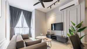 A modern living room with a sofa, two side tables, a TV, and a ceiling fan. - BeCentral i-City by Manhattan (Shah Alam)