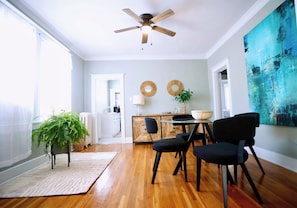 A dining area with a ceiling fan, a dining table with chairs, a potted plant, and a large abstract painting on the wall. - Charming Midtown home in the heart of Memphis (Memphis)