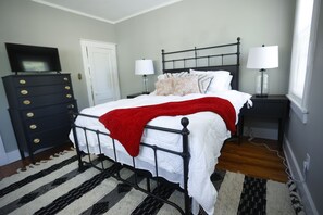 A bedroom with a bed, a dresser, a television, two bedside lamps, and a window. - Charming Midtown home in the heart of Memphis (Memphis)