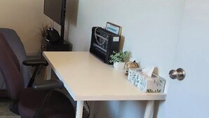 A desk with a chair, a potted plant, a small decorative item, and a door with a round handle.