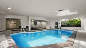 Una piscina al coperto con vista chiara sulla zona della piscina, un’area salotto e una porta che conduce in un’altra stanza.