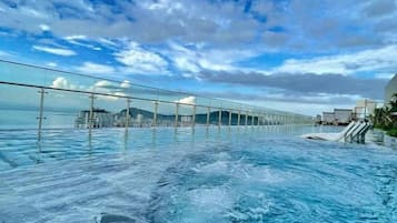 Una piscina infinita con vistas al océano y un puente.