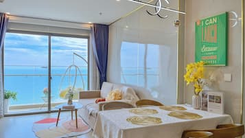A modern room with a balcony, a sofa, a dining table, and a decorative sign.