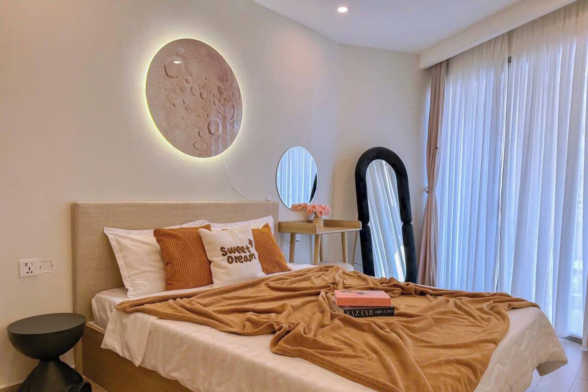 A modern bedroom with a bed, bedside table, and a wall-mounted circular light.