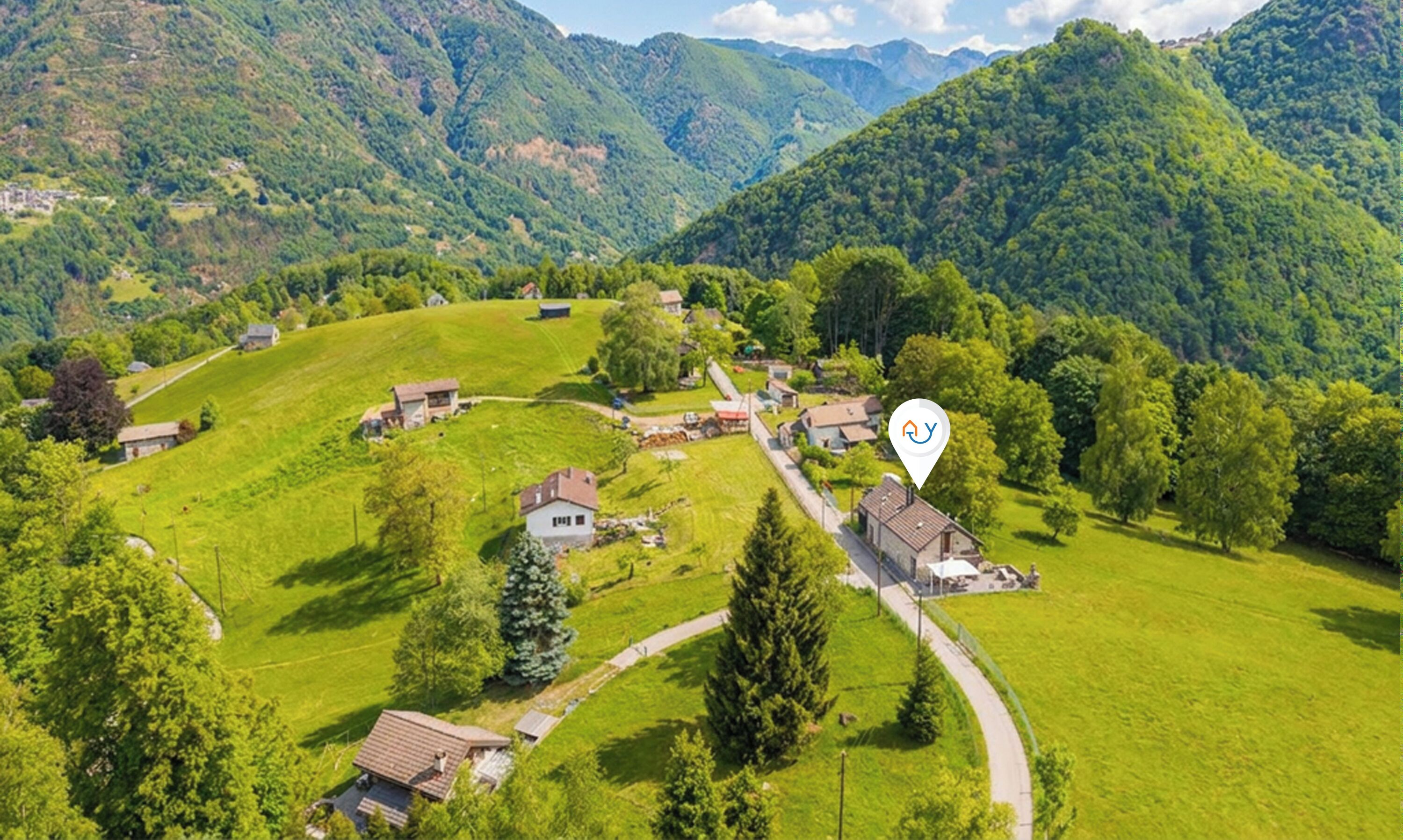 Ein ländliches Dorf mit Häusern und einer kurvenreichen Straße, umgeben von Bergen.