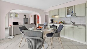 A modern kitchen with a dining area, featuring a central island, light-colored cabinets, and a tiled backsplash. - Panoramic Garden Lake View in Locarno Monti, Locarno, Switzerland (Locarno)