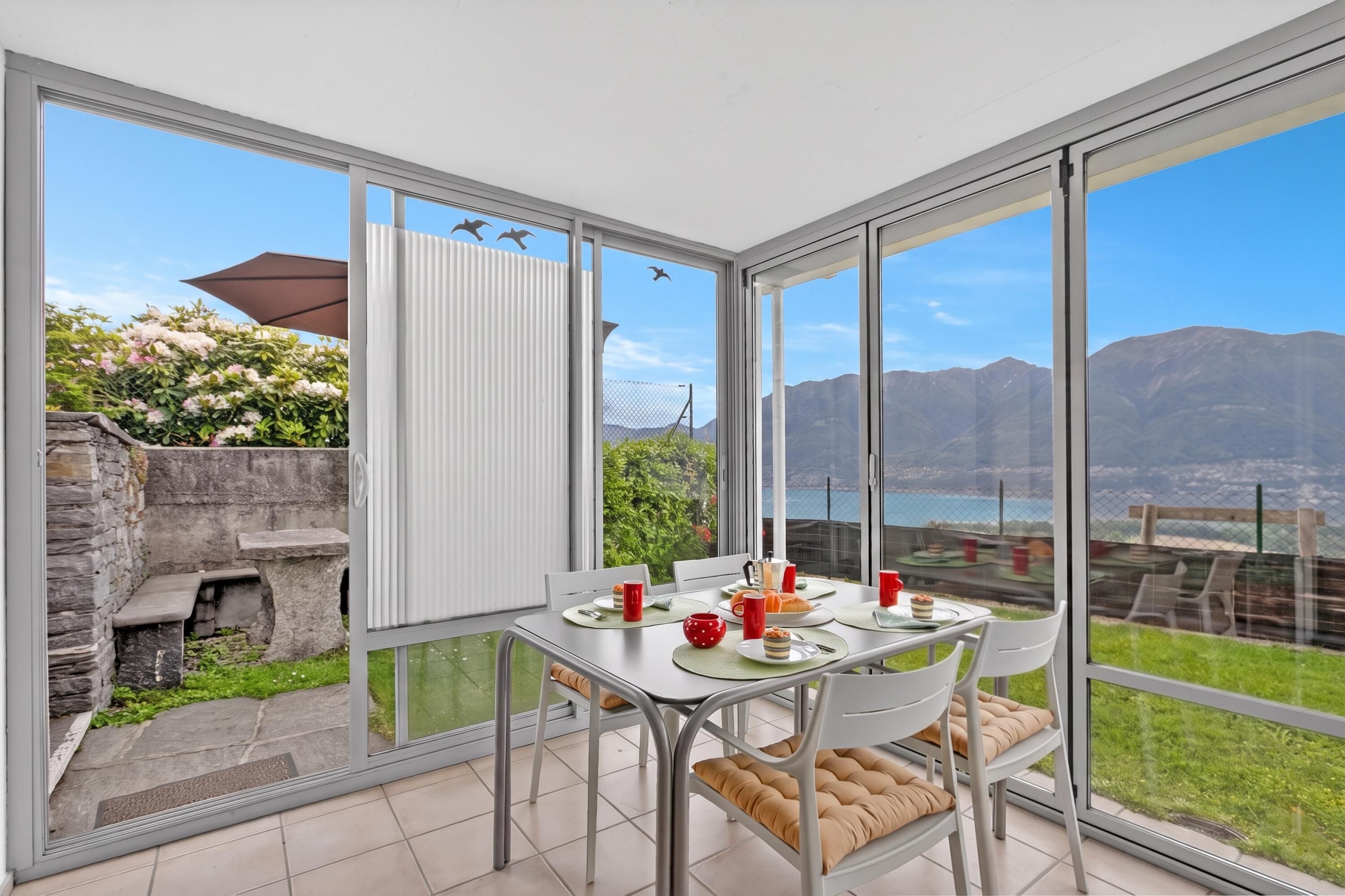 A dining area with a table set for two, overlooking a scenic view of mountains and a body of water.