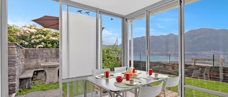 A dining area with a table set for two, overlooking a scenic view of mountains and a body of water.